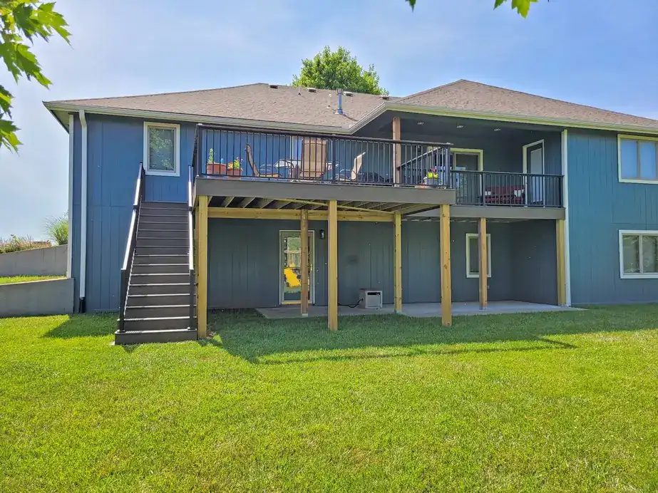 Rear of a house with blue siding, an elevated deck and an exterior stair
