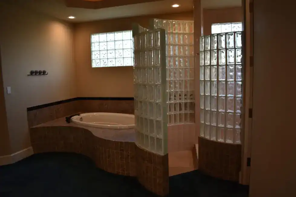 The Mosimann primary bath before PDQ: a dated drop-in tub and glass block wall
