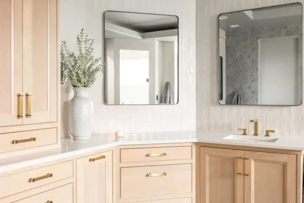 Remodeled primary bath with a light oak double vanity and two framed mirrors